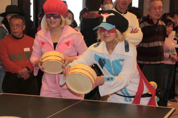 アニメのヤッターマン（ガンちゃん、アイちゃん）の格好をした女性が桶を持って構えている写真